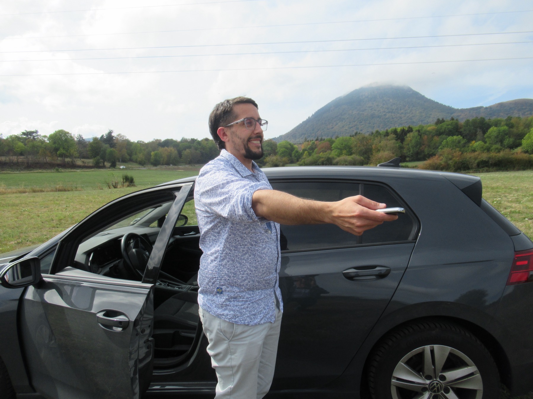 Sylvain Potier tend les clés d'une voiture, devant le puy de Dôme